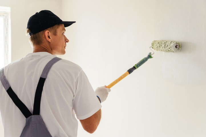 Mano usando un rodillo de pintura con la técnica correcta sobre una pared