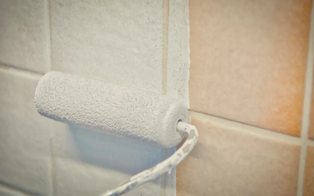 Rodillo pintando de blanco unos azulejos antiguos del baño